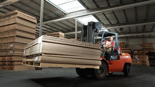 Gabelstapler transportiert Holzpaletten Gabelstapler transportiert Holz und Holzpaletten in Lager